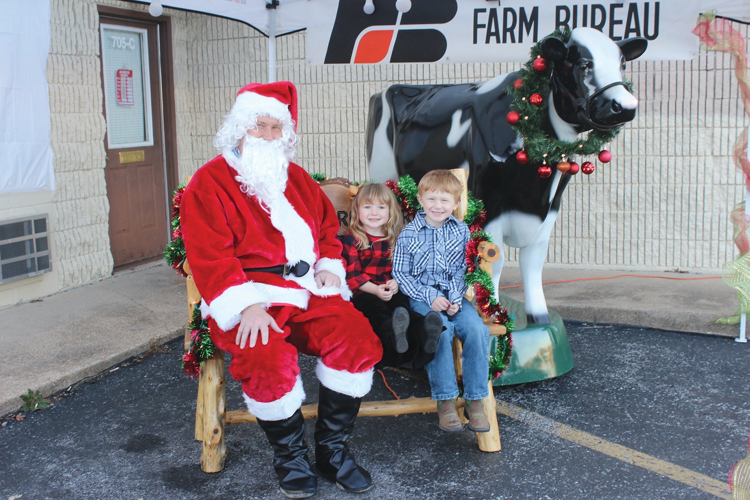 Grace Durney, 3, and GW Durney, 5, with Santa Claus and Sunnie, the Wright County Farm Bureau’s dairy cow.